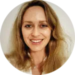 A woman with long, light brown hair and a light complexion smiles at the camera. She is wearing a white top against a plain, light background, giving a professional look—perfect for an evisort alternative profile photo.