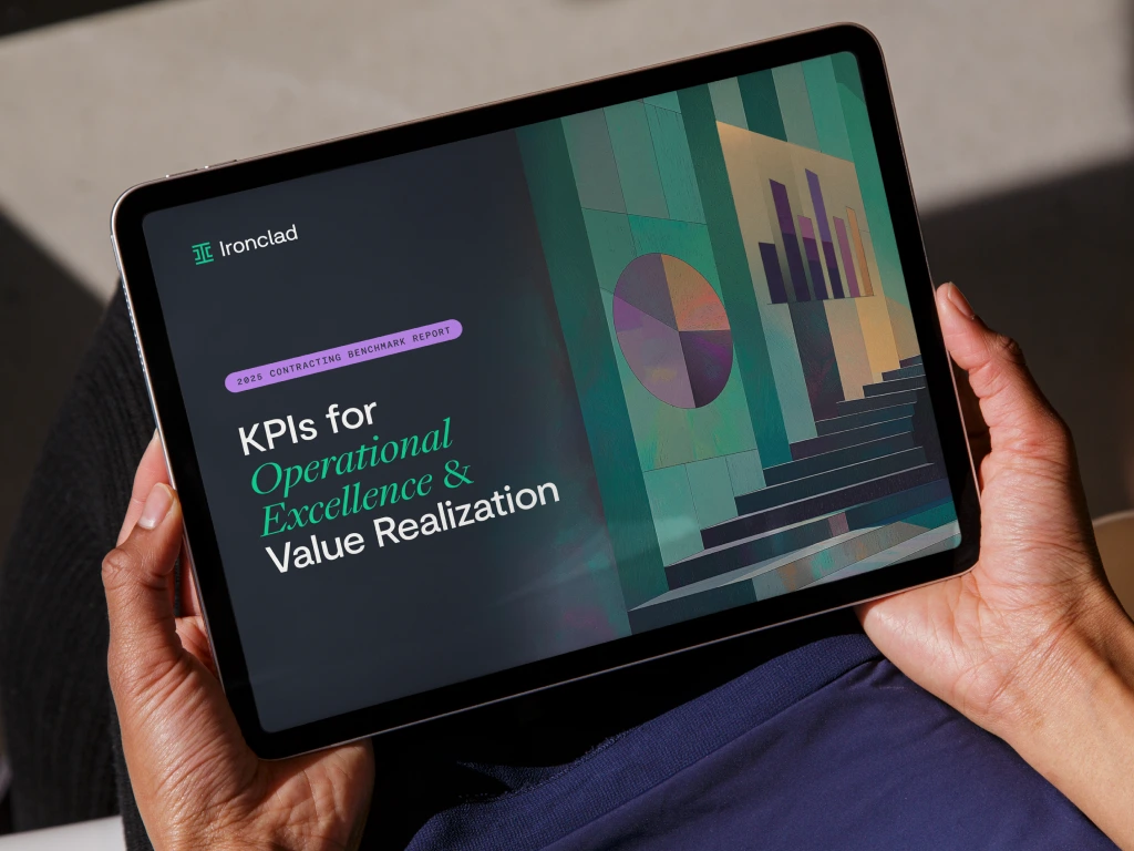 A person holds a tablet displaying a report titled KPIs for Operational Excellence & Value Realization by Ironclad, featuring a colorful abstract graphic with bar charts and geometric shapes.