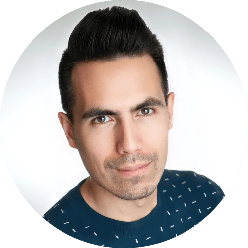 A young man with short, dark hair styled upward, wearing a navy blue shirt with a subtle white pattern, looks directly at the camera with a neutral expression, presenting a modern juro alternative style against a white background.