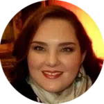 A woman with long brown hair smiles at the camera, wearing a light scarf and dark clothing. With a warm, orange background behind her, she embodies confidence—perfect for showcasing your top Evisort alternative.