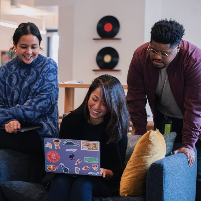 three people looking at a laptop