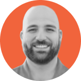 Portrait of a smiling bearded man with a shaved head, shown in grayscale within an orange circular frame on a light gray background, representing the approachable face behind ironclad clm expertise.