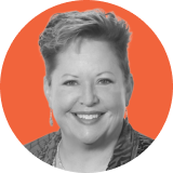 Black and white portrait of a smiling woman with short hair, wearing earrings and a patterned top, set against an orange circular background, representing the professionalism of Ironclad CLM.