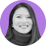 Smiling woman with long straight hair, wearing a dark turtleneck sweater, pictured in black and white against a purple circular background, symbolizing confidence and clarity like an ironclad clm.